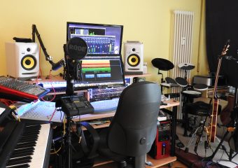 Wie alles anfing - Auf dem Bild sieht man ein kleines Musikstudio mit Keyboard, Schalgzeug, Gitarre, Bass ein einem Homstudio-Arbeitsplatz